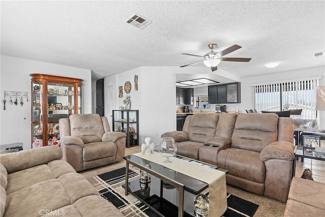 living room with ceiling fan, plenty of natural light, and a textured ceiling