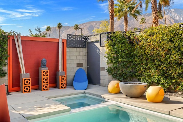 view of pool featuring an in ground hot tub, a mountain view, and a patio