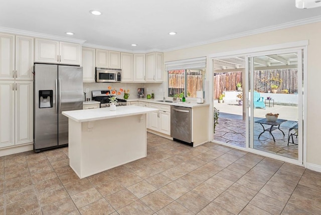 kitchen featuring crown molding, appliances with stainless steel finishes, a center island, and sink