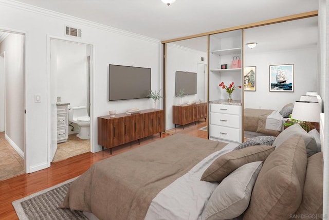 bedroom featuring crown molding, ensuite bath, and light hardwood / wood-style floors