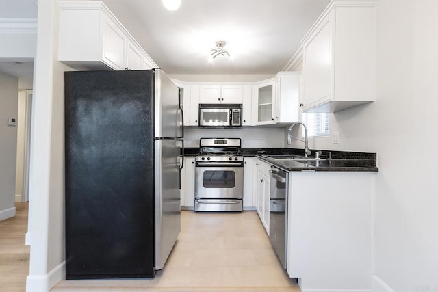 kitchen featuring appliances with stainless steel finishes, sink, dark stone counters, and white cabinets