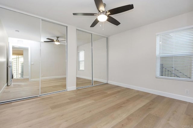 unfurnished bedroom featuring multiple windows, light hardwood / wood-style flooring, and multiple closets