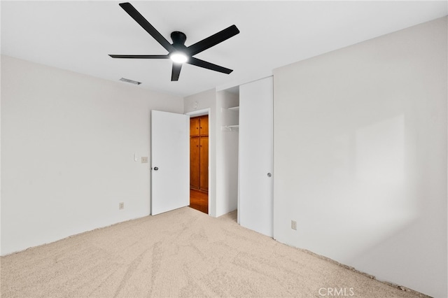 unfurnished bedroom featuring ceiling fan, a closet, and light carpet