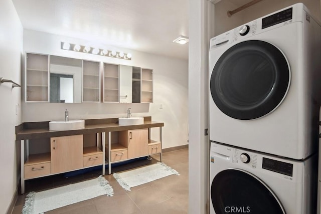 laundry area featuring tile patterned floors, stacked washer / drying machine, and sink