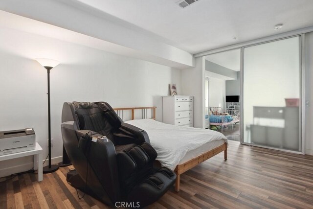 bedroom with expansive windows and dark wood-type flooring