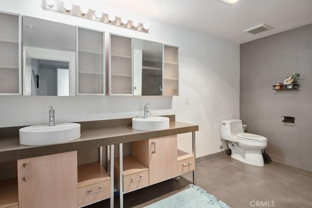 bathroom with vanity, tile patterned floors, tile walls, and toilet