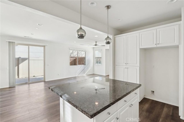 kitchen with dark stone counters, dark hardwood / wood-style flooring, hanging light fixtures, and white cabinets