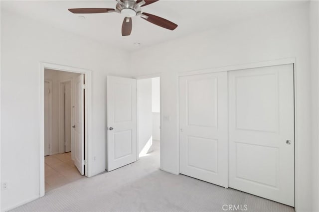 unfurnished bedroom with ceiling fan, a closet, and light carpet