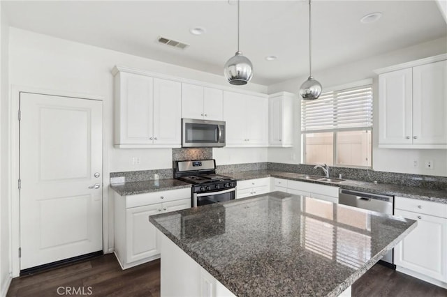 kitchen with sink, stainless steel appliances, white cabinets, and a kitchen island