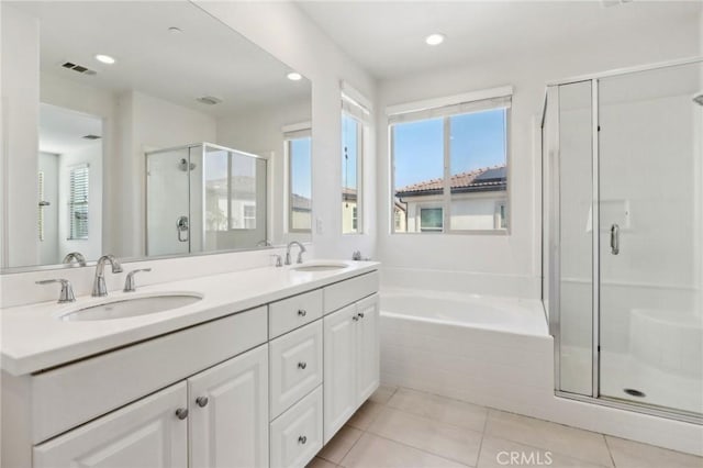 bathroom with a healthy amount of sunlight, independent shower and bath, tile patterned flooring, and vanity