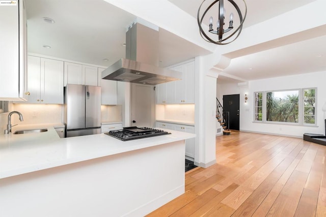 kitchen featuring sink, white cabinets, island exhaust hood, kitchen peninsula, and stainless steel appliances