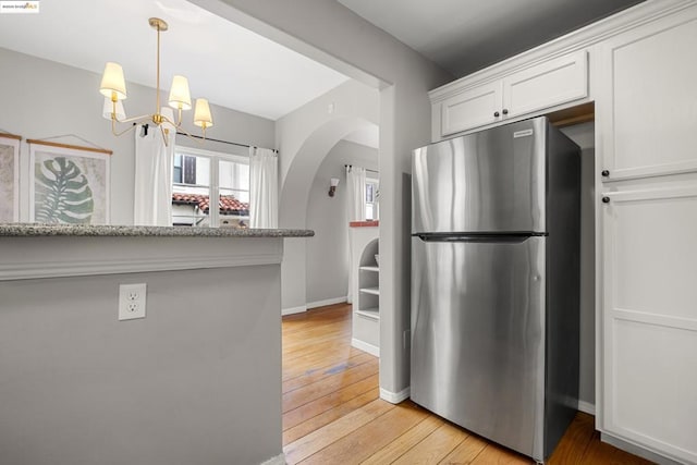 kitchen with white cabinetry, light stone countertops, stainless steel fridge, and light hardwood / wood-style floors