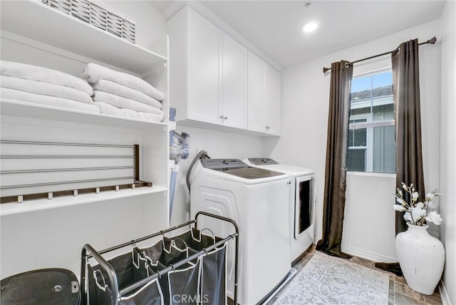 clothes washing area featuring independent washer and dryer and cabinets