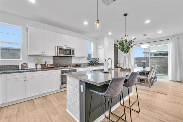 kitchen with visible vents, a sink, light wood-style flooring, appliances with stainless steel finishes, and white cabinetry