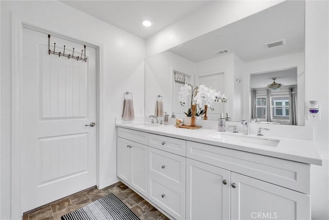 bathroom featuring visible vents, a sink, and double vanity
