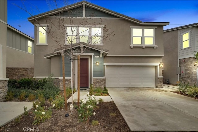 view of front facade featuring concrete driveway, an attached garage, stone siding, and stucco siding