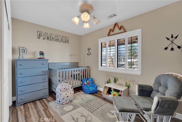 bedroom featuring hardwood / wood-style floors and a crib