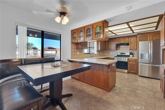 kitchen featuring sink, tile countertops, appliances with stainless steel finishes, ceiling fan, and decorative backsplash