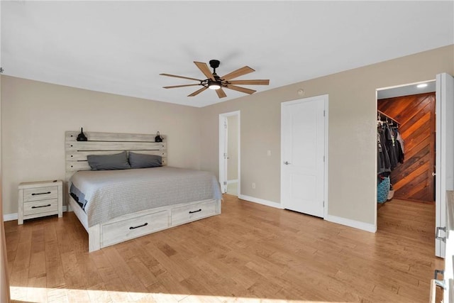 bedroom featuring ceiling fan, a walk in closet, light hardwood / wood-style floors, and a closet