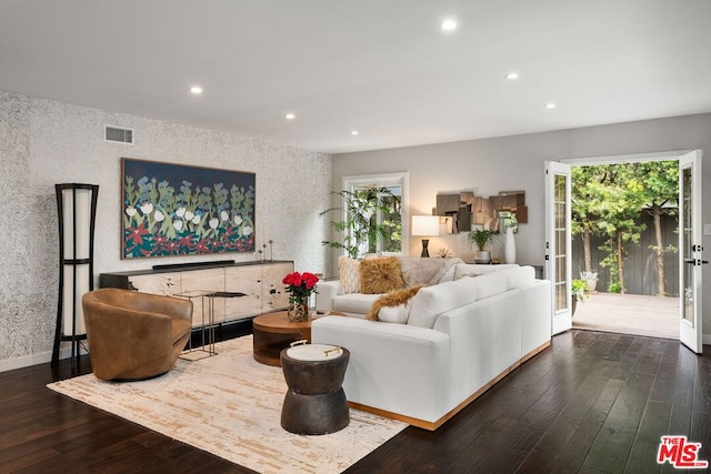 living room with a wealth of natural light, dark hardwood / wood-style floors, and french doors