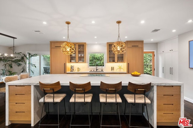 kitchen featuring a large island, dark wood-type flooring, and a kitchen bar