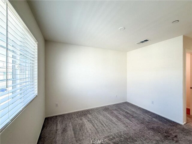 spare room with dark colored carpet