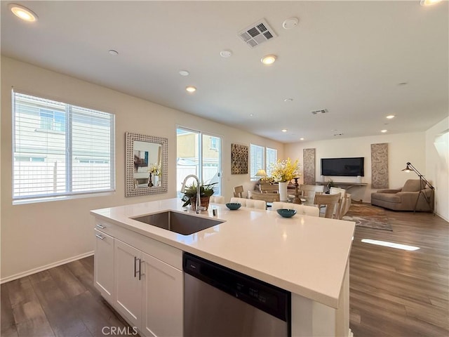 kitchen with sink, dishwasher, white cabinetry, dark hardwood / wood-style floors, and an island with sink