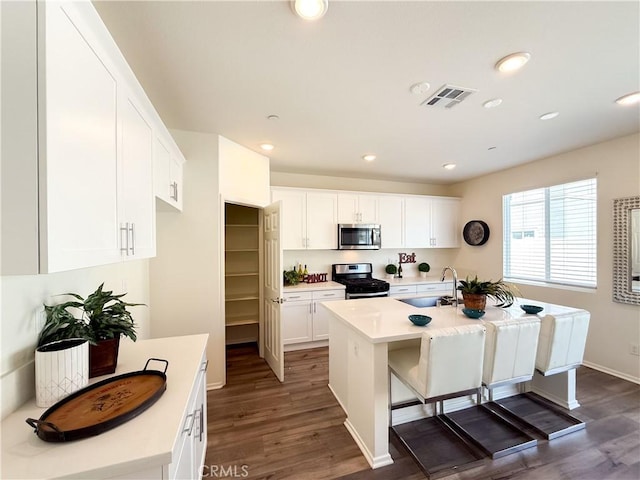 kitchen featuring white cabinetry, appliances with stainless steel finishes, sink, and a center island with sink