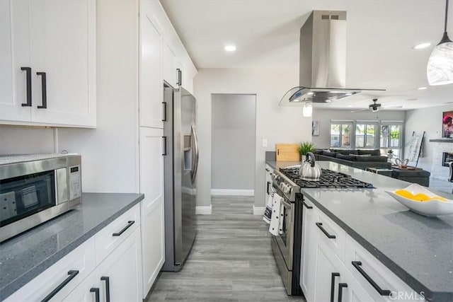 39120 Paradise Way, Cathedral City, CA 92234 - kitchen featuring white cabinets, dark stone counters, hanging light fixtures, island exhaust hood, and stainless steel appliances