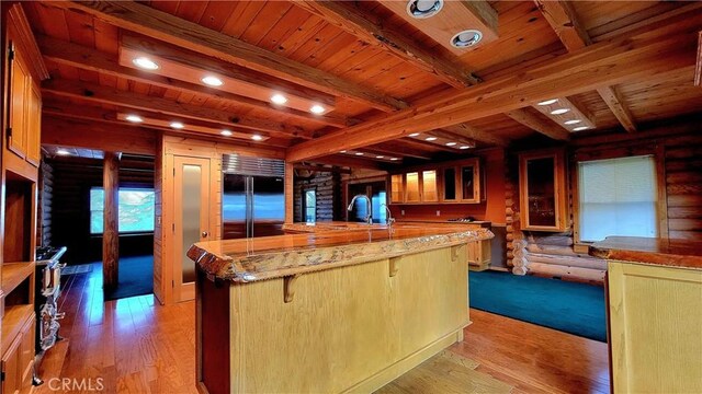 kitchen with a breakfast bar, beamed ceiling, log walls, built in refrigerator, and kitchen peninsula