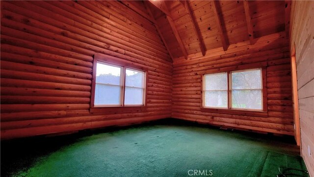 unfurnished room with lofted ceiling with beams, dark colored carpet, and a wealth of natural light