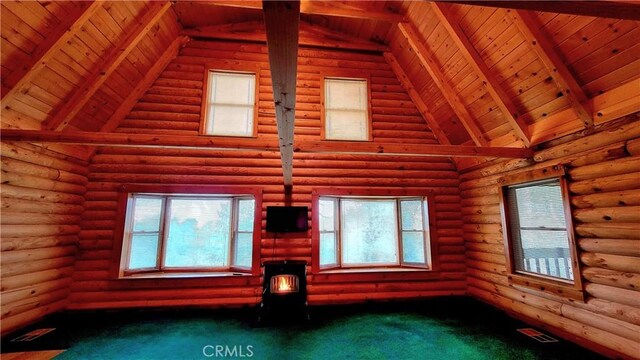 unfurnished living room featuring beamed ceiling, wood ceiling, carpet, and a wealth of natural light