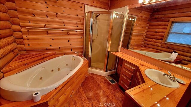 bathroom with plus walk in shower, wood-type flooring, rustic walls, and vanity