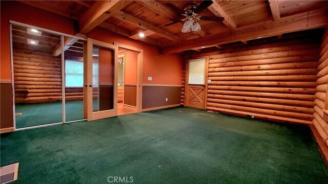 carpeted empty room with ceiling fan, rustic walls, wooden ceiling, french doors, and beamed ceiling