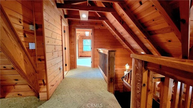 hall with wooden ceiling, lofted ceiling with beams, and wood walls