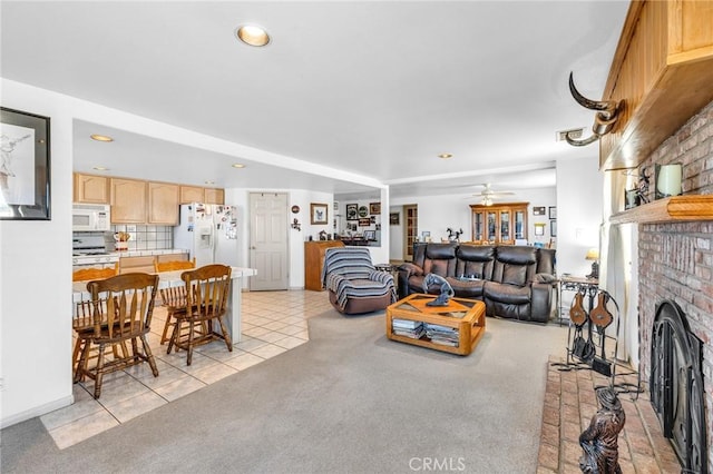 living room featuring a brick fireplace, light colored carpet, and ceiling fan