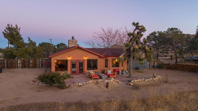 back house at dusk featuring a patio