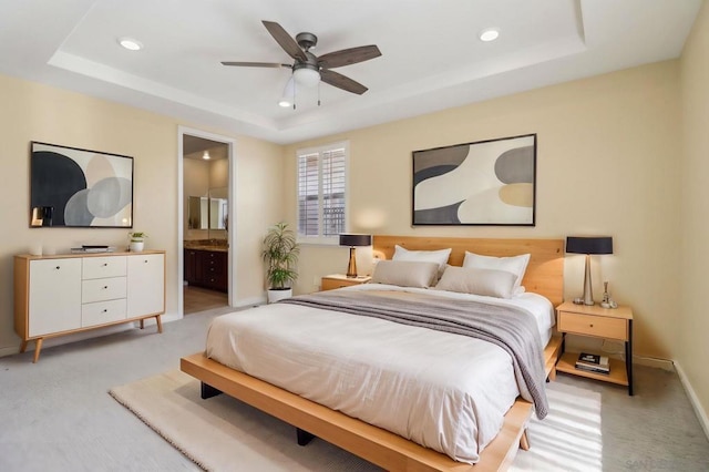 carpeted bedroom featuring connected bathroom, a tray ceiling, and ceiling fan