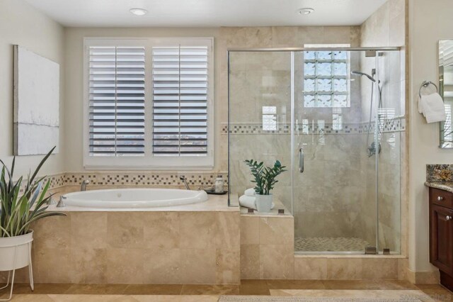 bathroom featuring tile patterned floors, vanity, and shower with separate bathtub