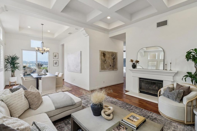 living room with dark wood-type flooring, a high ceiling, coffered ceiling, a notable chandelier, and beamed ceiling