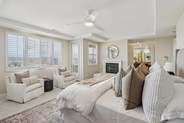 carpeted bedroom with a tray ceiling and ceiling fan