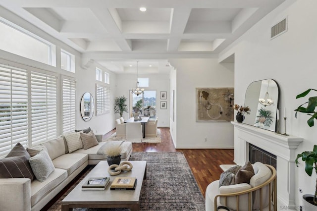 living room featuring an inviting chandelier, beam ceiling, a towering ceiling, coffered ceiling, and dark hardwood / wood-style flooring