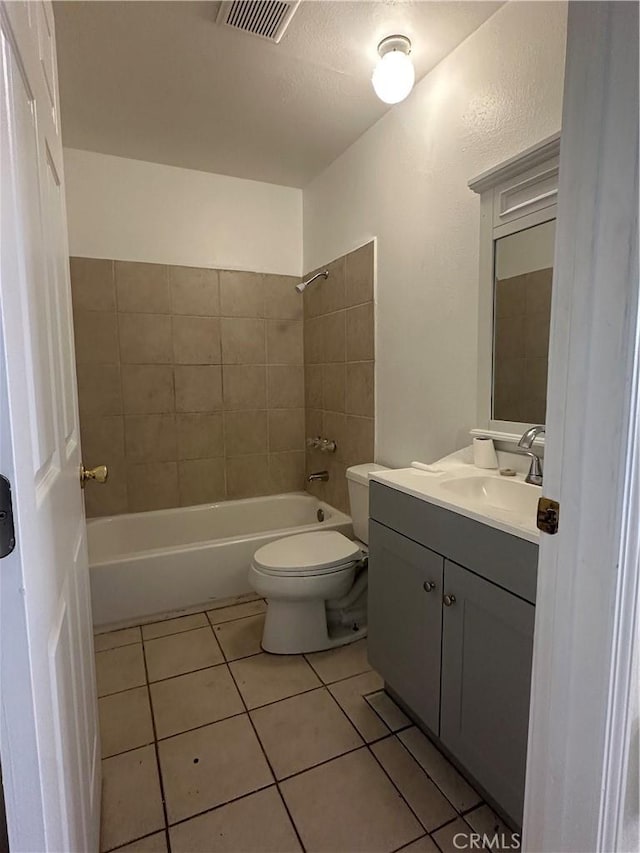 full bathroom featuring tile patterned flooring, vanity, tiled shower / bath, and toilet