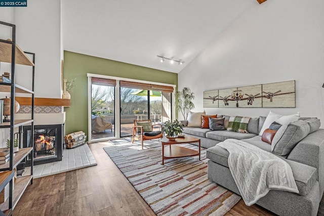 living room featuring a multi sided fireplace, track lighting, high vaulted ceiling, and hardwood / wood-style floors