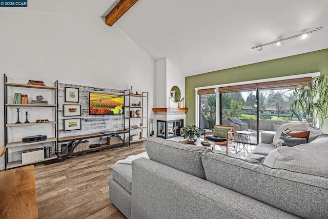 living room featuring hardwood / wood-style floors, beam ceiling, high vaulted ceiling, a multi sided fireplace, and track lighting