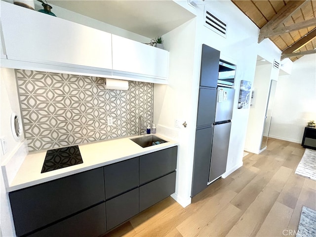 kitchen featuring sink, decorative backsplash, stainless steel refrigerator, and light wood-type flooring