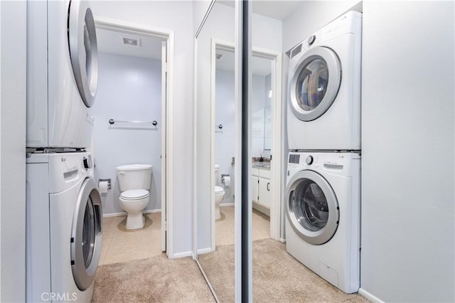 laundry area featuring stacked washer and dryer and light carpet