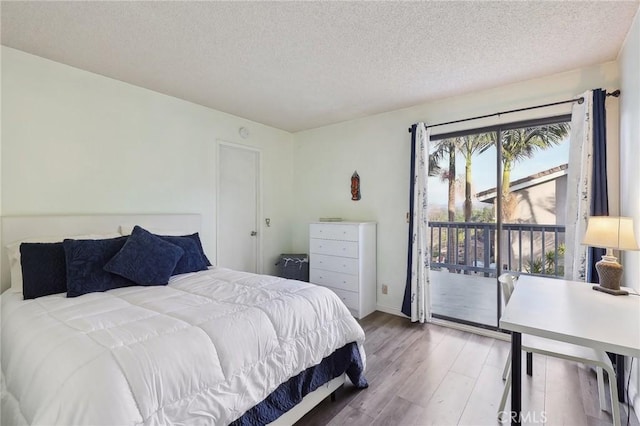 bedroom featuring access to outside, wood finished floors, and a textured ceiling