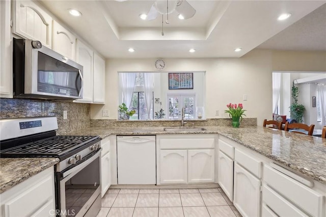 kitchen featuring appliances with stainless steel finishes, kitchen peninsula, sink, and a raised ceiling