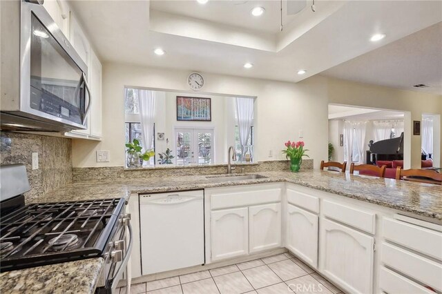 kitchen featuring appliances with stainless steel finishes, white cabinetry, sink, a tray ceiling, and french doors